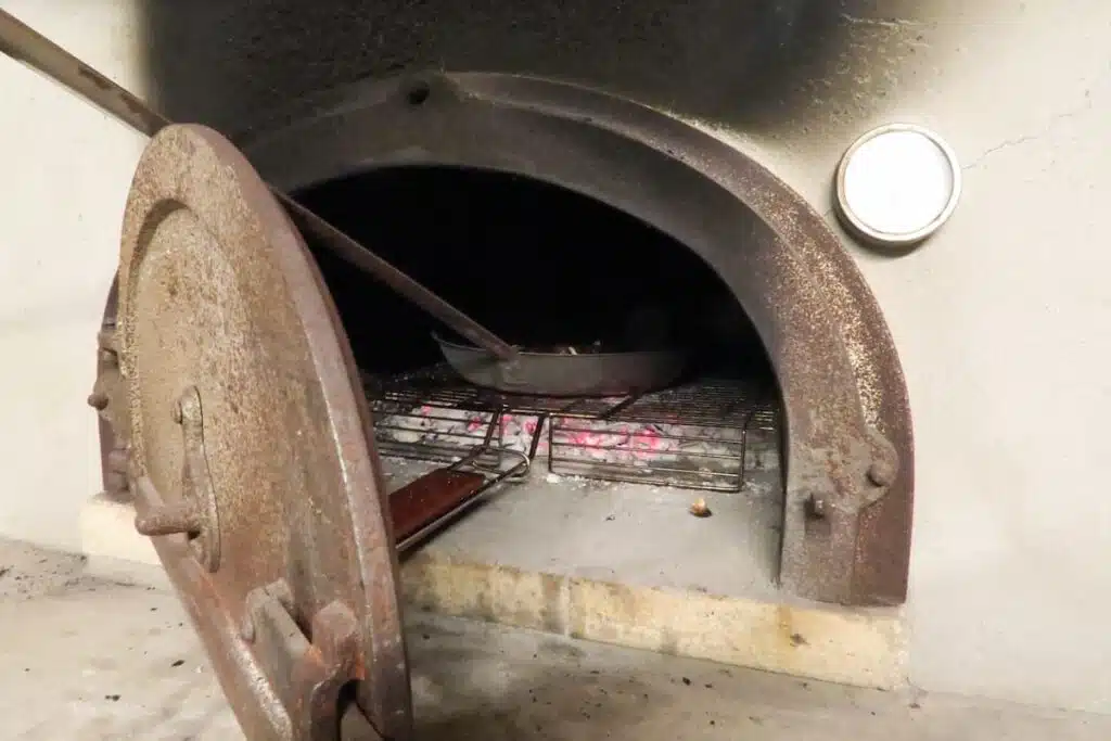 Poêle à long manche sur une grille, à l'entrée du four, porte en fonte ouverte