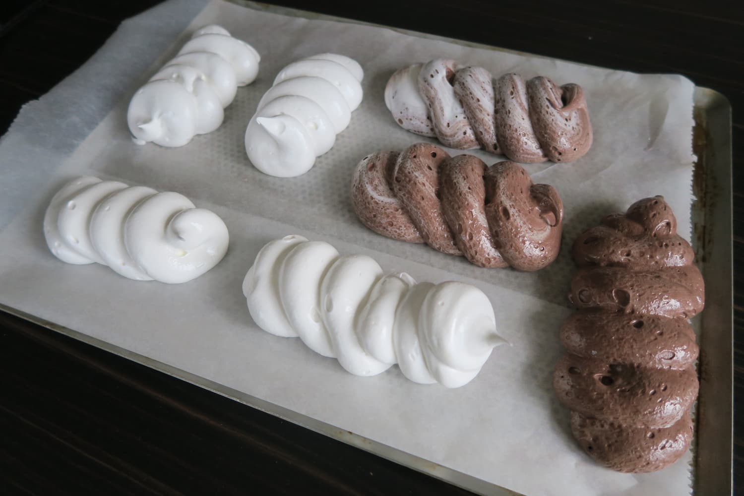 Meringues nature et au chocolat crues sur une plaque, avant cuisson