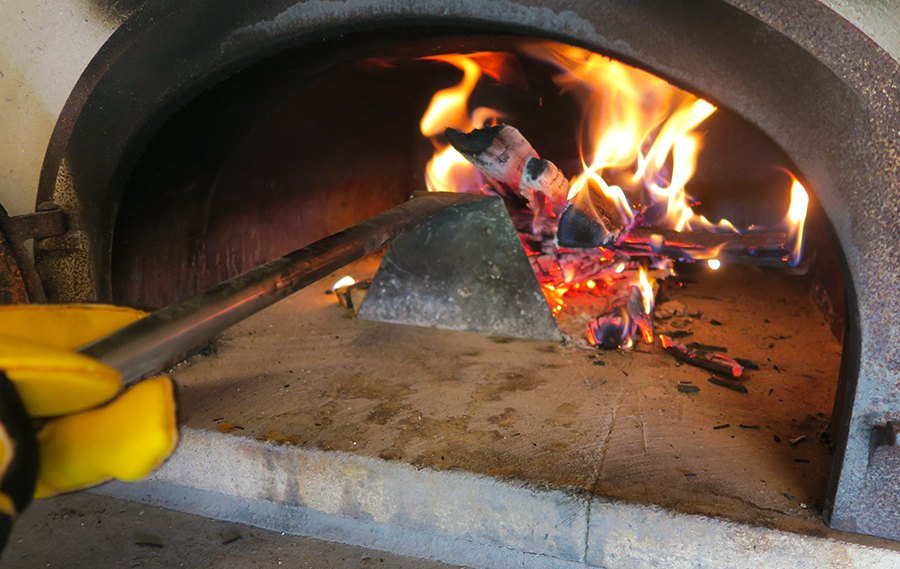Raclette à braises en action dans le four à bois